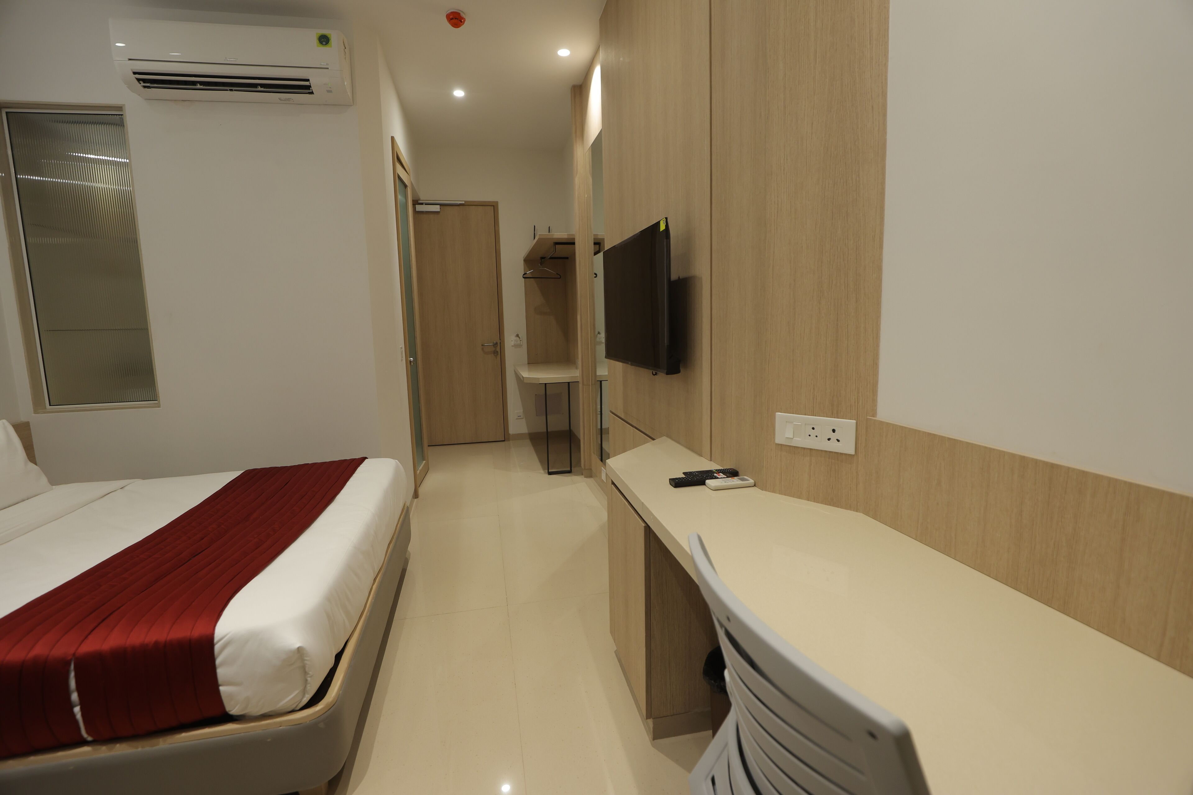 Una habitación de hotel con cama, escritorio, televisión y armario.
