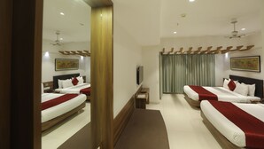 A hotel room with two beds, a large mirror, a flat-screen TV, and a ceiling fan. - Hotel Shreeji Vatika-Airport Road (Surat)