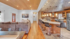 A modern kitchen with a central island, bar stools, and a dining area with a wooden table and chairs.