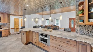 A spacious kitchen with a large island, wooden cabinets, and a unique ceiling design.