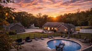 A residential area with a swimming pool, two houses, and a sunset.