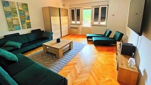 Ein modernes Wohnzimmer mit einer Sofagarnitur, einem Couchtisch und einem Fernseher.