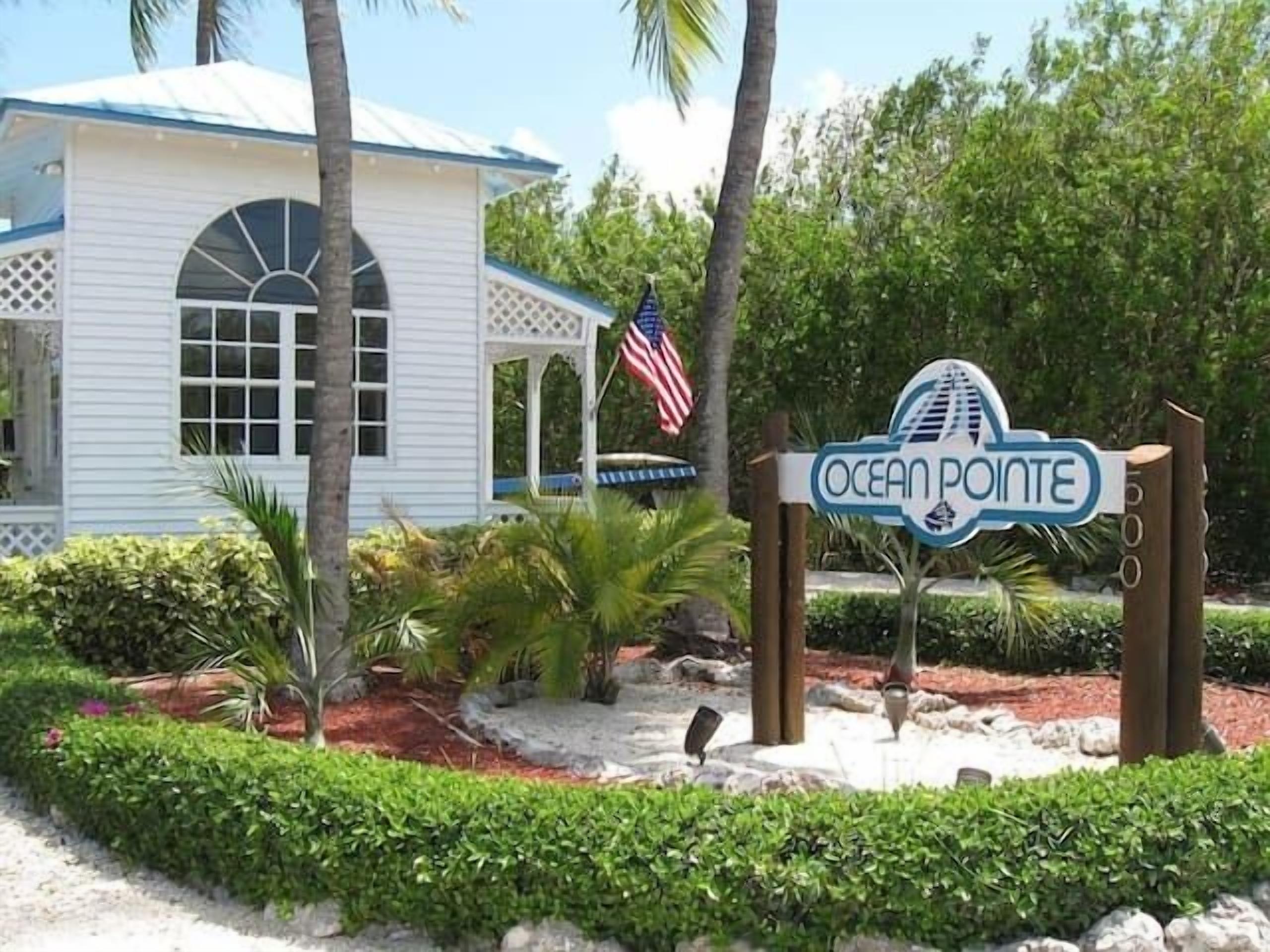 A sign for Ocean Pointe with a white building in the background.
