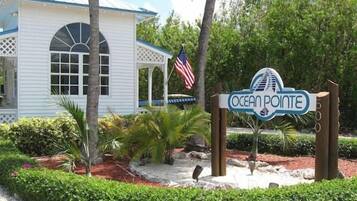 A sign for Ocean Pointe with a white building in the background.