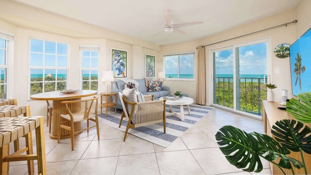 A spacious living area with a dining set, a sofa, and a coffee table. There are large windows offering a view of the ocean. - Marina and Ocean View, 2 Bed, 2 Bath End Unit 4201 (Tavernier)
