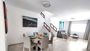 A modern living room with a dining area, a staircase, and a large window with curtains. - Villa Anny, heated pool, ideal for families! (PLAYA BLANCA)