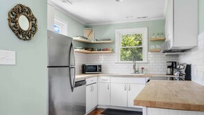 A modern kitchen with white cabinets, a stainless steel refrigerator, a microwave, and wooden countertops. - Water Views, Minutes to Downtown & Folly Beach! (Charleston)