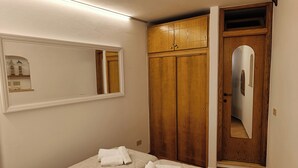 A bedroom with two beds, a wooden wardrobe, a mirror, and a door with a mirror. - Casa Vacanza Opuntia (Sperlonga)