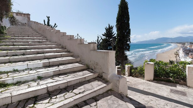 A stone staircase leading down to a beach with a view of the ocean and mountains in the distance. - Casa Vacanza Opuntia (Sperlonga)