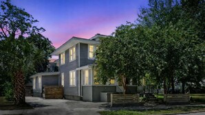 A two-story residential building with a modern design, featuring a driveway and a well-maintained lawn.