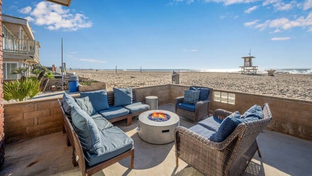 Un patio con mobiliario de mimbre y una chimenea, con vista a la playa.