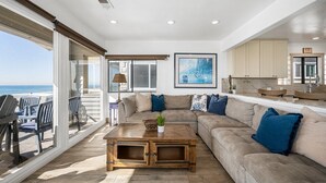 A spacious living area with a large sofa, a coffee table, and a view of the ocean. - 5-Bedroom Oceanfront Escape with Private Balcony (Newport Beach)