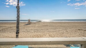 A beach with a lifeguard tower and a palm tree. - 5-Bedroom Oceanfront Escape with Private Balcony (Newport Beach)
