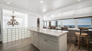A spacious kitchen with a large island, wooden flooring, and a view of the ocean. - 5-Bedroom Oceanfront Escape with Private Balcony (Newport Beach)
