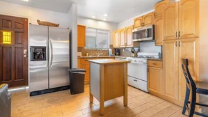 A modern kitchen with wooden cabinets, stainless steel appliances, and a central island. - Cozy 2-Bedroom Getaway (Newport Beach)