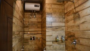 A bathroom with a wooden wall design, a toilet, a shower area, and a towel rack. - Hotel Leosh Lansdwone (Lansdowne)