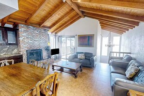 A spacious living room with a stone fireplace, a wooden dining table, and leather sofas.