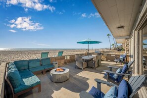 A beachside patio with a fire pit, outdoor furniture, and a view of the ocean.