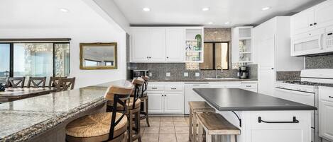 Una cocina moderna con armarios blancos, encimeras de granito y una isla grande.