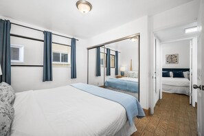 A hotel room with two beds, a large mirror, and a wooden floor.