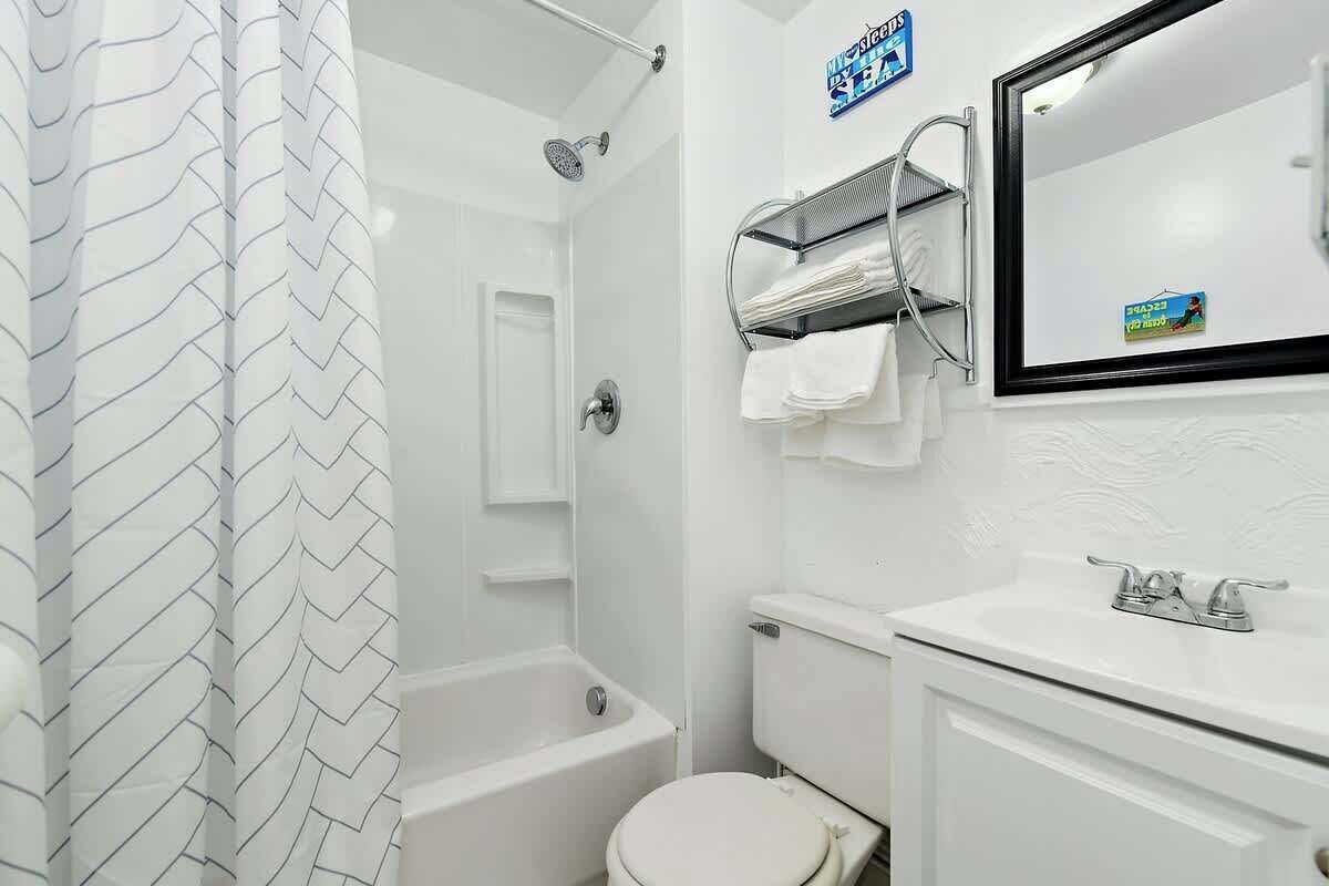 Een badkamer met douche, toilet, wastafel en handdoekhouder.