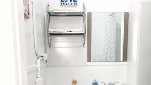 Et lille, hvidt badeværelse med toilet, håndvask, spejl og et skilt med teksten 'LOVE OCEAN CITY' over toilettet.