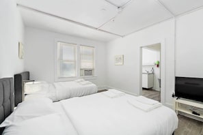 Une chambre d’hôtel avec deux lits, une télévision, un bureau et une kitchenette.