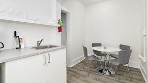 Una cocina moderna con un lavamanos, un bloque de cuchillos y un extintor. Hay un comedor con una mesa redonda y cuatro sillas.