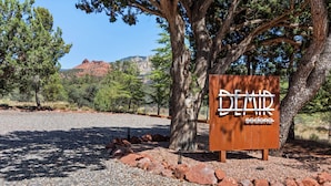 A sign with the text "DEAN" and "sodong" in a natural setting with trees and a gravel path.