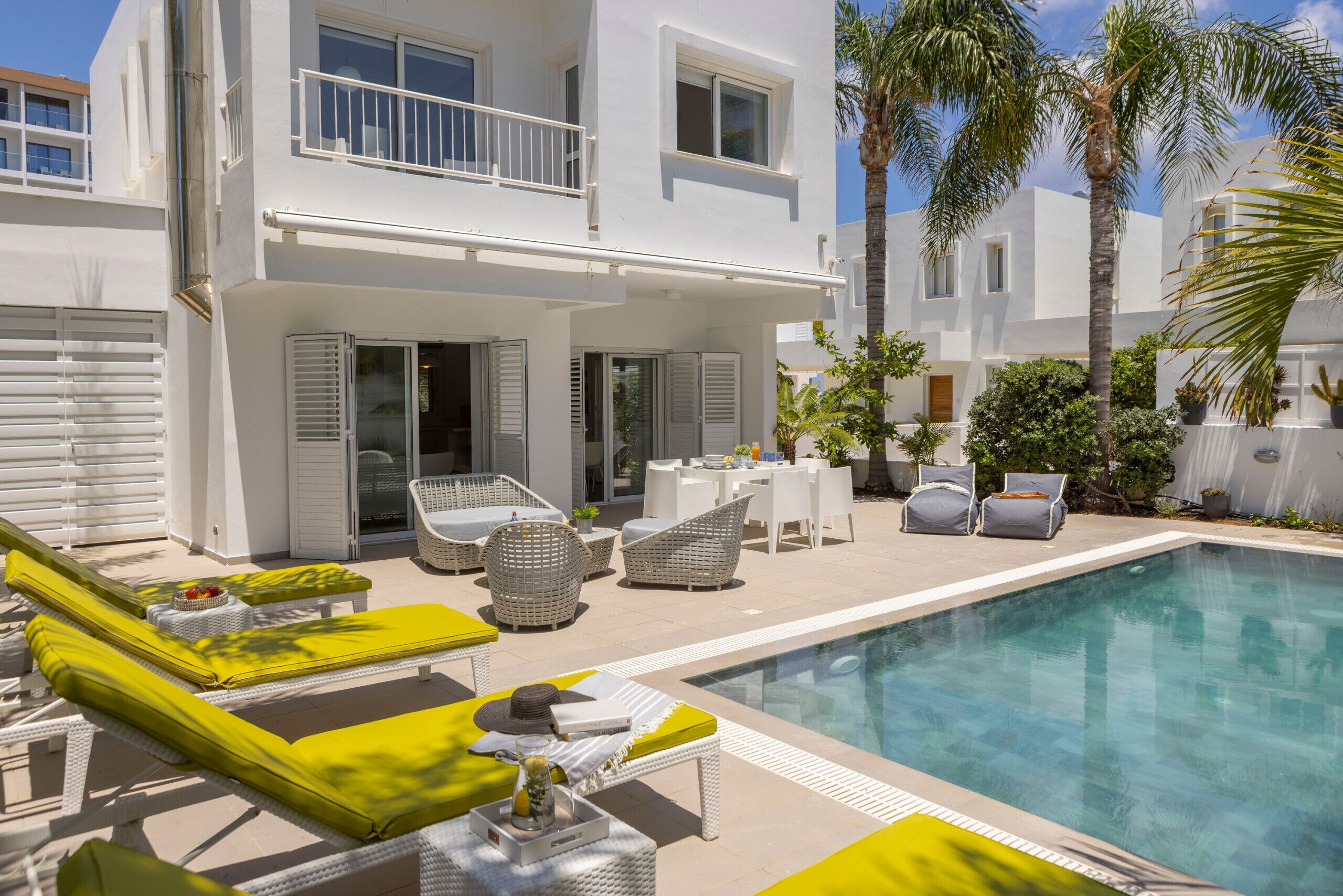 Une maison moderne à deux étages, dotée d’une piscine, d’un espace salon extérieur et d’un balcon.
