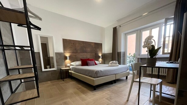 A modern bedroom with a bed, bedside tables, a chair, a radiator, and a window with curtains.