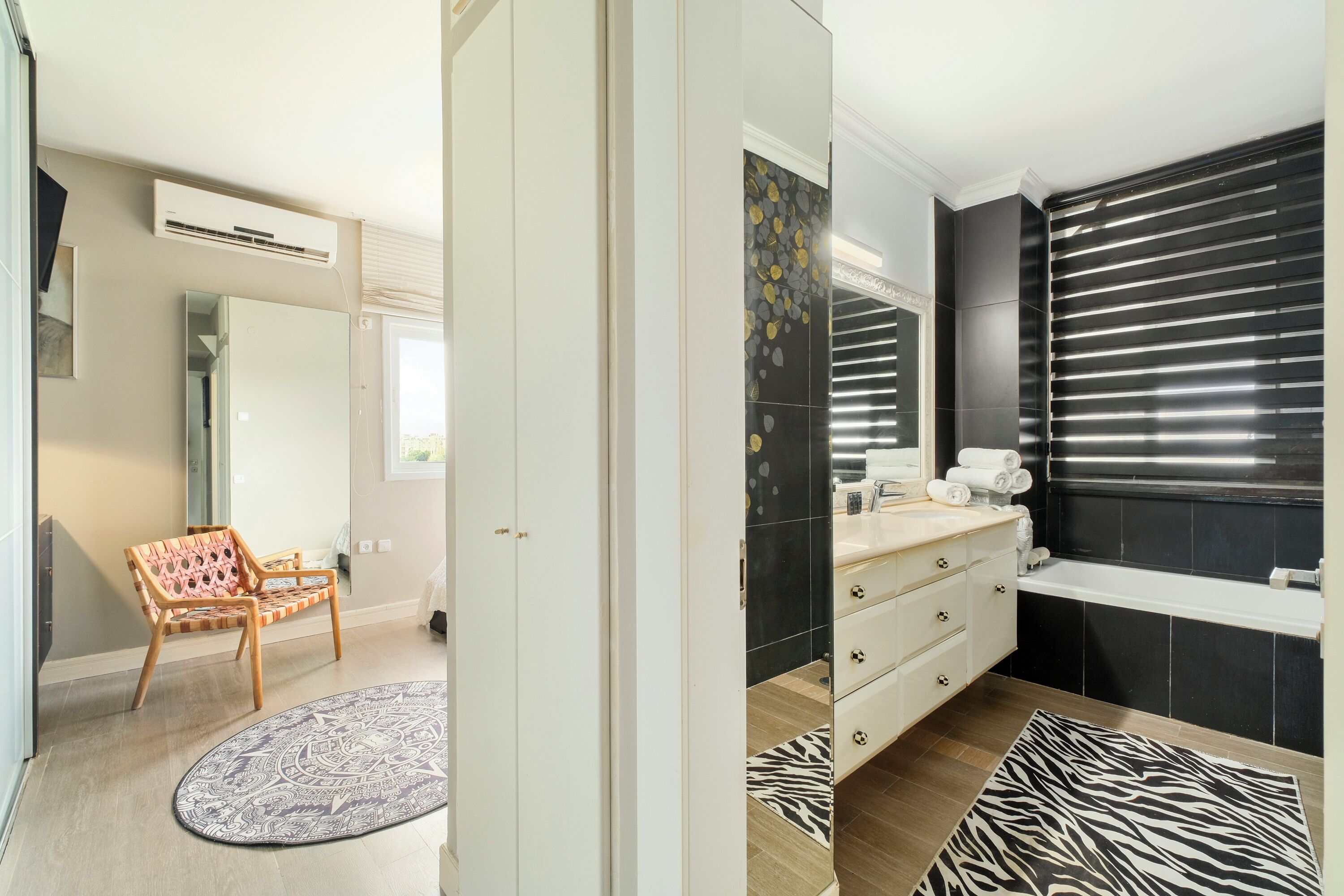 Een moderne badkamer met een zwart bad, een wit wastafelmeubel en een vloerkleed met zebraprint.