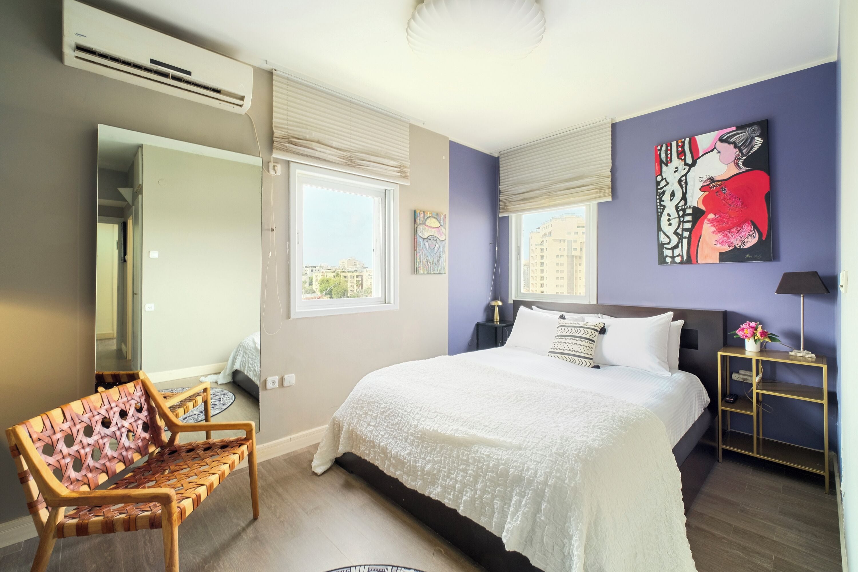 A bedroom with a large bed, a chair, a nightstand, and a painting on the wall.