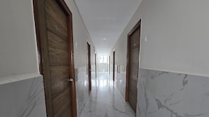 A corridor with marble flooring, wooden doors, and a bright ceiling. - Om Sri Vigneshwara Palani Grand Hotel (Hyderabad)