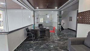 A modern office space with a marble floor, a reception desk, and a seating area with chairs. - Om Sri Vigneshwara Palani Grand Hotel (Hyderabad)