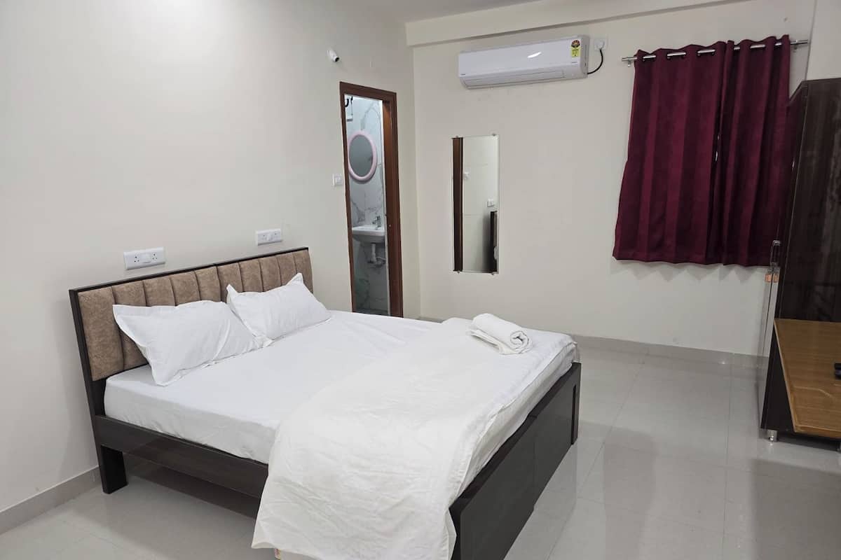 A neatly made bed with white bedding, a wooden headboard, and a bedside table with a lamp.