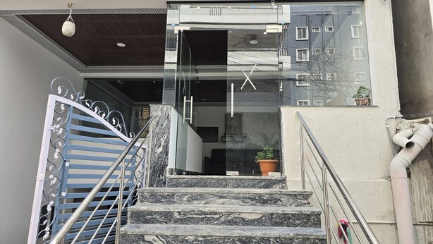A staircase leading to a building entrance with a metal gate, a glass door, and a potted plant near the door. - Om Sri Vigneshwara Palani Grand Hotel (Hyderabad)