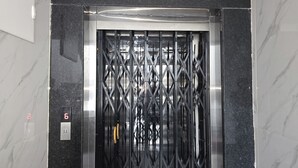 An elevator with a metal gate and a sign indicating the sixth floor. - Om Sri Vigneshwara Palani Grand Hotel (Hyderabad)