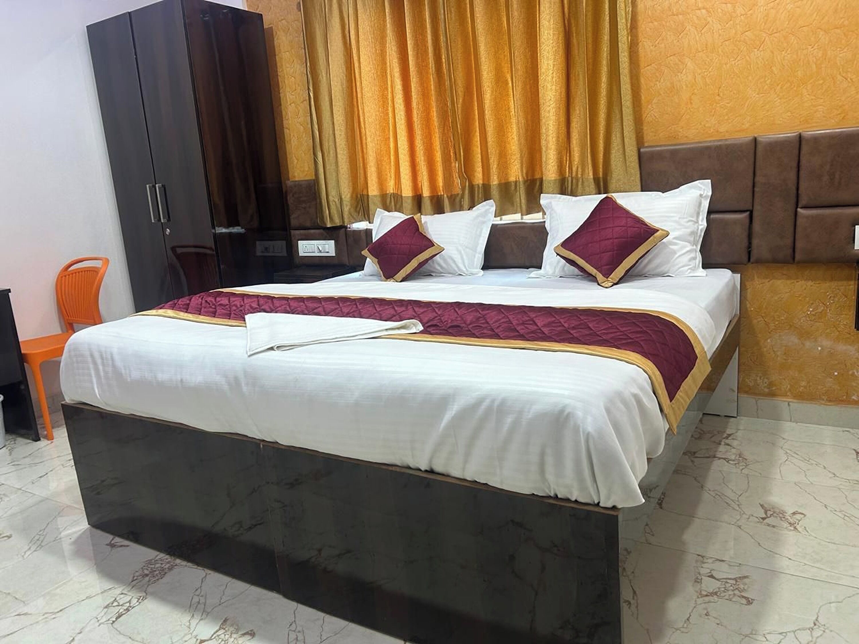 A neatly made bed with a white and maroon bedspread, two pillows, and a folded white towel.