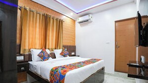 A hotel room with a bed, curtains, an air conditioning unit, a wardrobe, and a small table. - A White Pearl Suites (Bengaluru)
