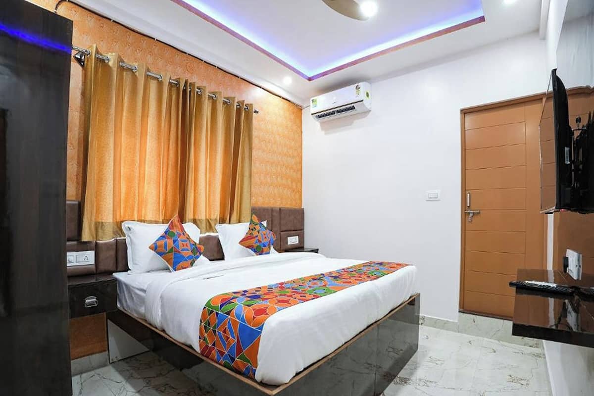 Una habitación de hotel con cama, cortinas, aire acondicionado, armario y una mesita.