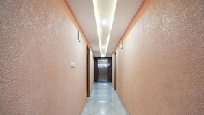 A hallway with a marble floor and peach-colored walls, leading to a darkened room at the end. - A White Pearl Suites (Bengaluru)