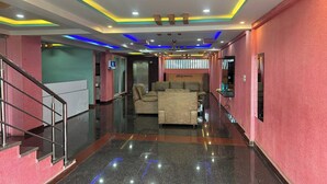 A hotel lobby with a modern design, featuring a central seating area, a staircase, and a reception desk. - A White Pearl Suites (Bengaluru)