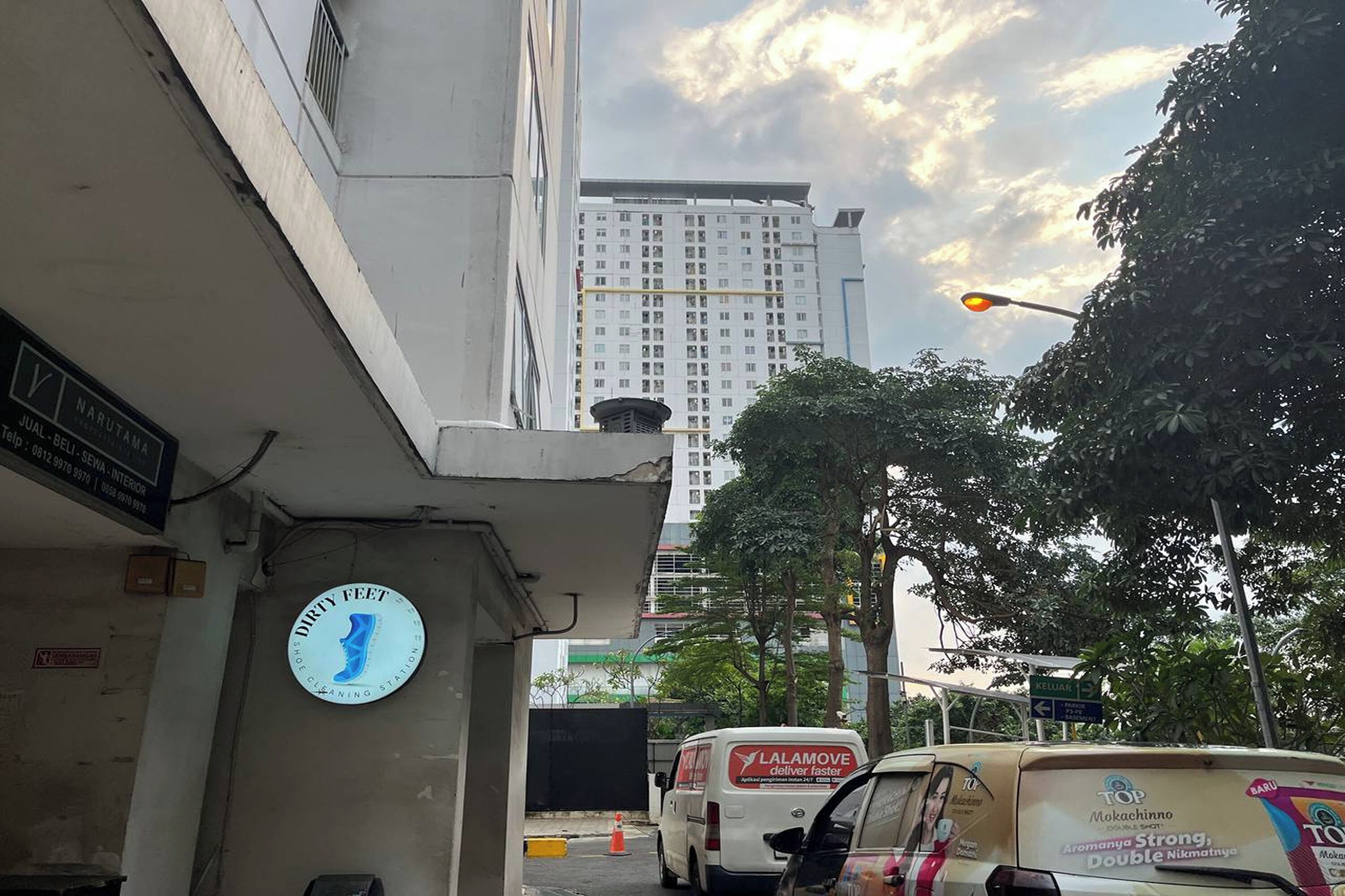 Vista de calle con un edificio que dice 'NARUTAMA' y un cartel que dice 'DIRTY FEET' en la pared.