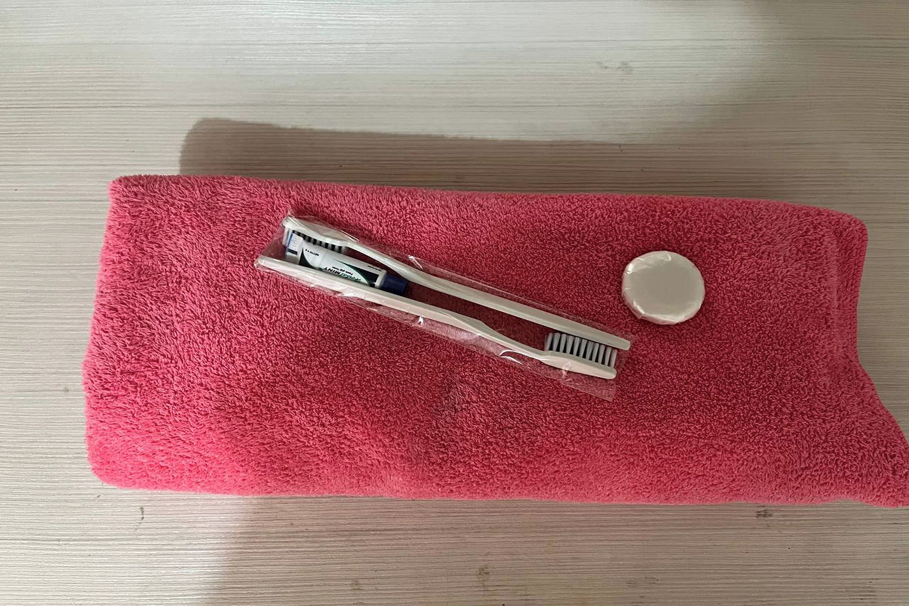 Een rode handdoek met een pincet en een klein bakje op een houten oppervlak.