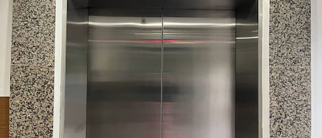 An elevator with a digital display reading "LG" and a red emergency button.