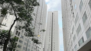 A high-rise residential building with multiple floors, large windows, and a central air conditioning unit.