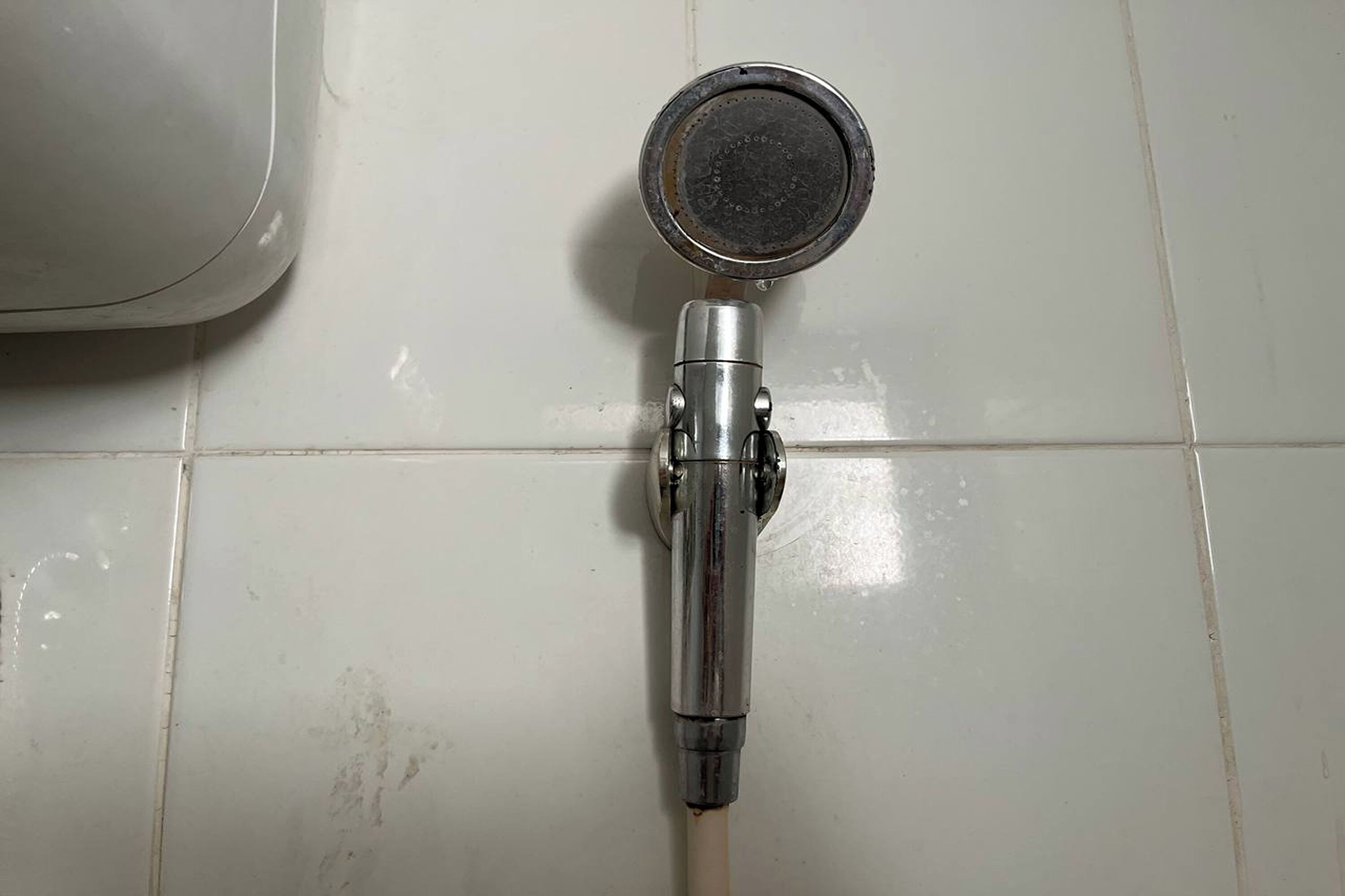 A showerhead mounted on a tiled wall.
