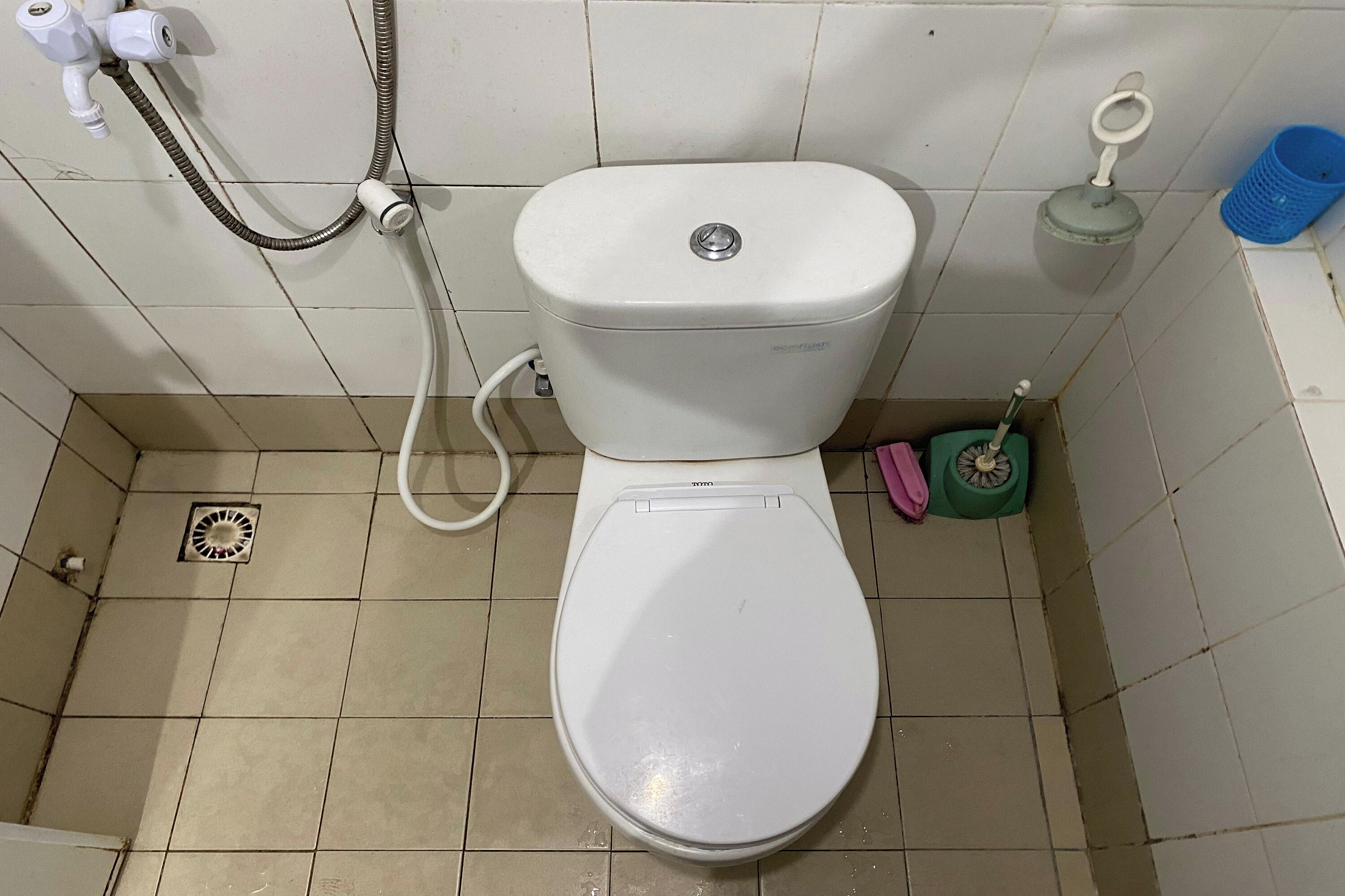 Sanita branca com função bidé, uma pequena lixeira e uma escova para casa de banho.