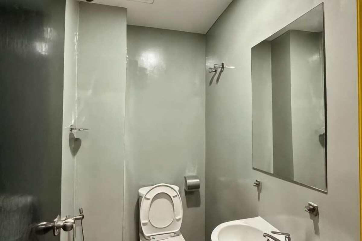 A bathroom with a toilet, sink, mirror, and shower.